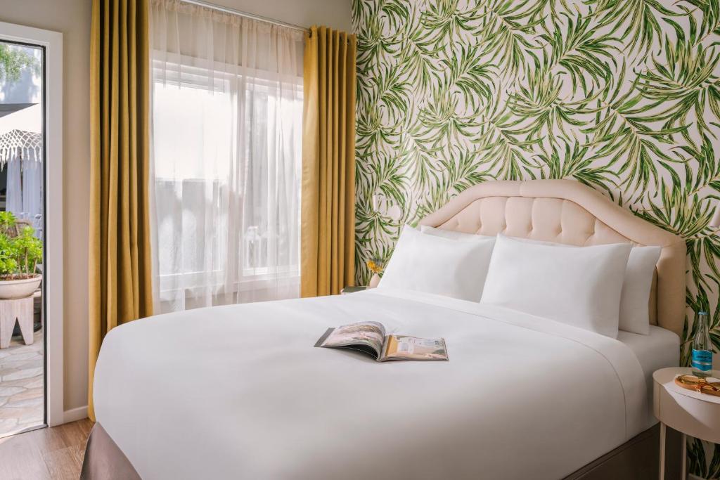 a bedroom with a white bed with a book on it at Beverly Terrace powered by Sonder in Los Angeles