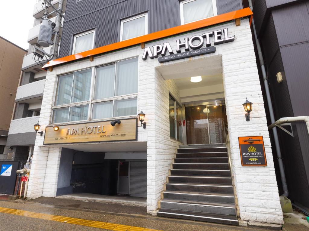 ein Hotelgebäude mit einer Treppe davor in der Unterkunft APA Hotel Niigata Higashinakadori in Niigata