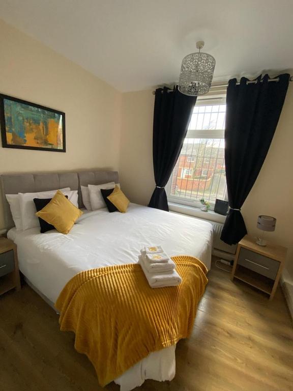 1 bed Flat ''Beta'' in Dewsbury road, Leeds في Hunslet: غرفة نوم بسرير كبير عليها بطانية صفراء