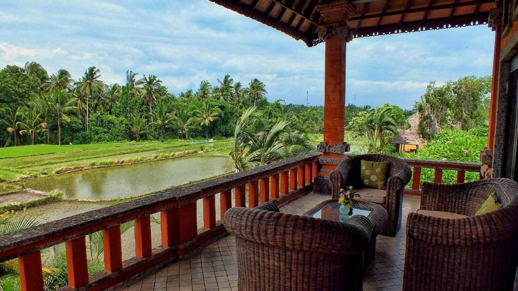 a balcony with chairs and a view of a river at Mandala Desa in Sukawati