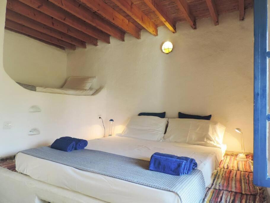 Lovely independent room in Ecovilla on the beach في Apolakkiá: غرفة نوم مع سرير أبيض كبير مع وسائد زرقاء