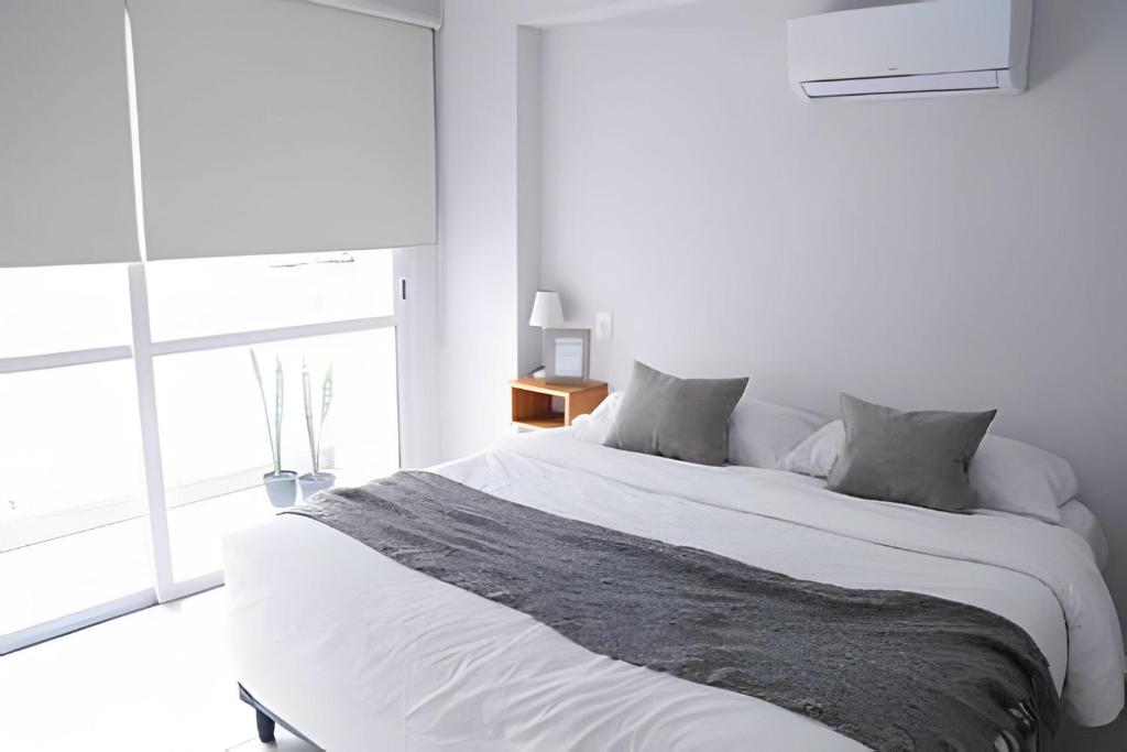 ein weißes Schlafzimmer mit einem großen Bett und einem Fenster in der Unterkunft Romeo Apt, p/ 4 personas, en el centro de Salta in Salta