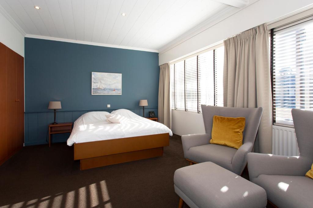 a bedroom with blue walls and a bed and a chair at Restaurant-Hotel de Watergeus in Noorden