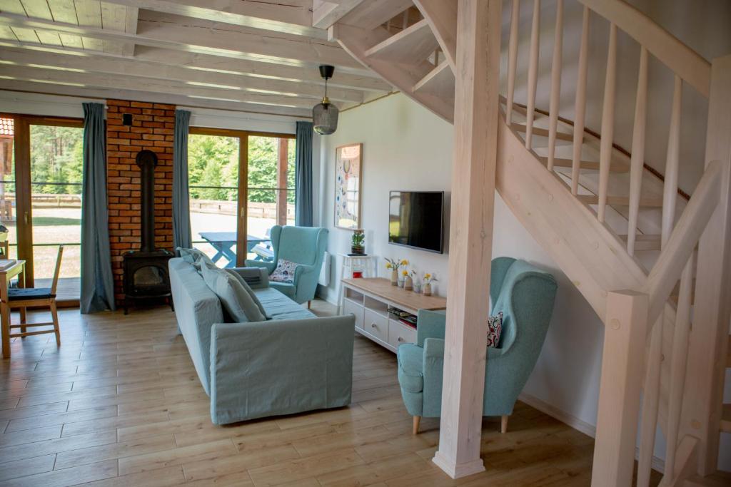 een woonkamer met blauwe stoelen en een trap bij Biały Bez Ostoja Bukowo in Borowy Młyn