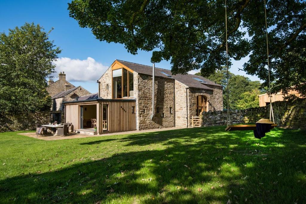 een stenen huis in een tuin met een schommel bij Williamston Barn in Slaggyford