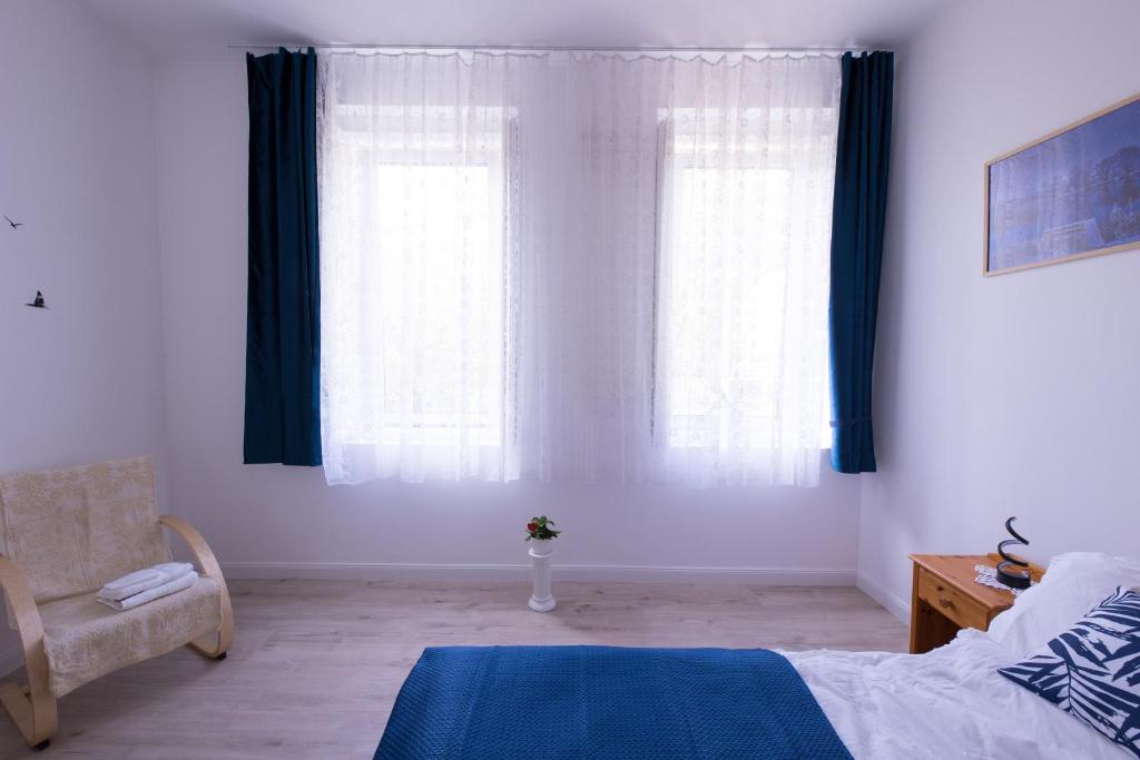 sypialnia z niebieskimi zasłonami, łóżkiem i krzesłem w obiekcie Wagner Villa 902 w Budapeszcie