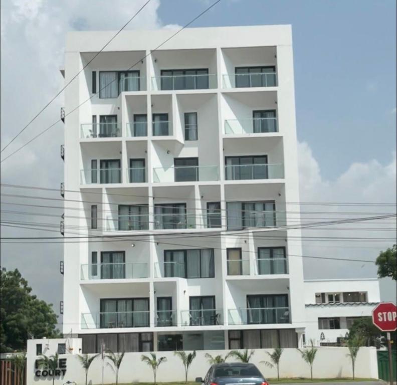 a white building with a car parked in front of it at Pine Court in Accra