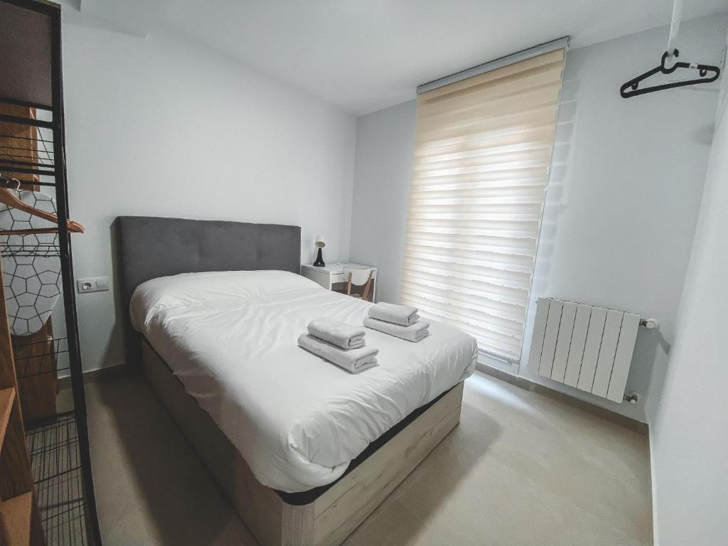 1 dormitorio con 1 cama con sábanas blancas y ventana en Casa San Juan - Habitaciones privadas Logroño, en Logroño
