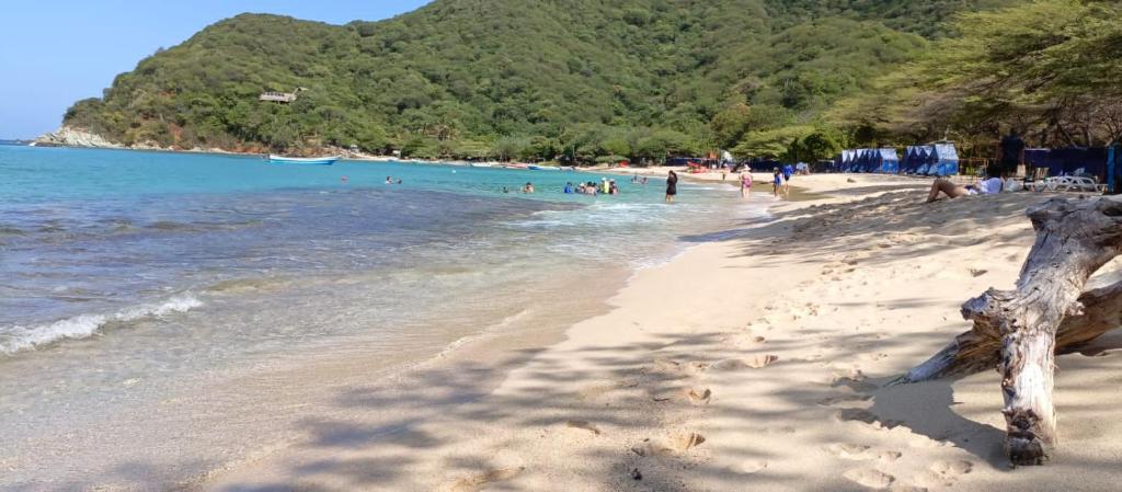 a beach with a bunch of people in the water at Mirador Playa Cristal Tayrona in Santa Marta