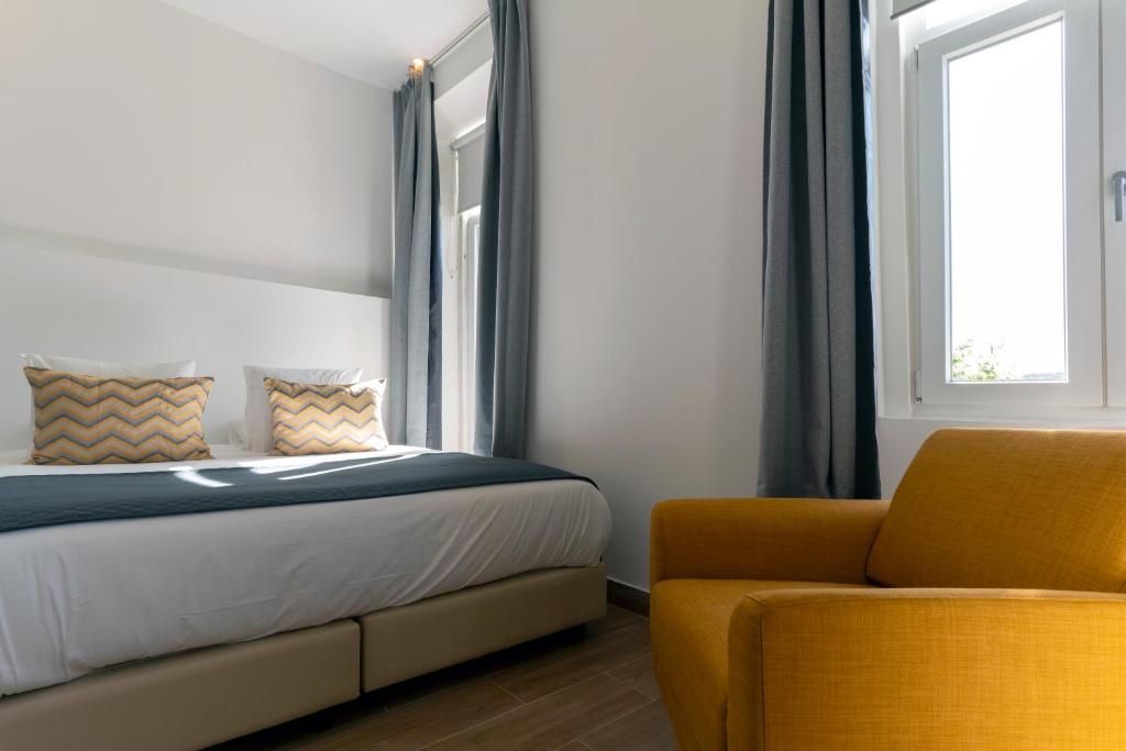 a bedroom with a bed and a yellow chair at Come Inn Sintra in Sintra