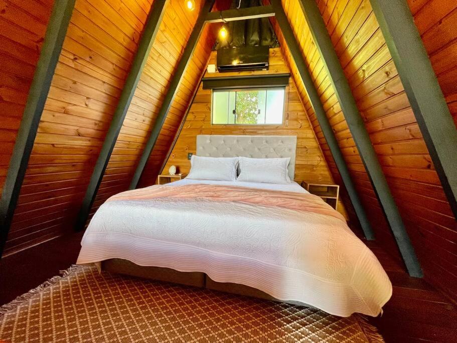 ein Schlafzimmer mit einem Bett in einem Holzhaus in der Unterkunft Chalé no Litoral 01 in Torres