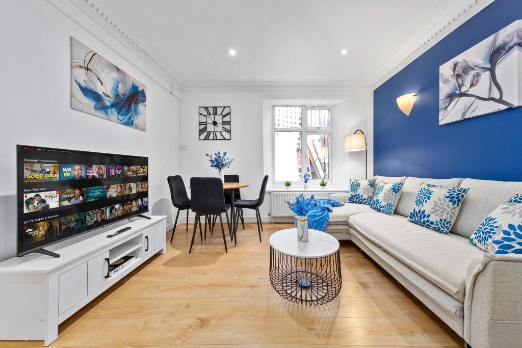 a living room with a couch and a tv at Kensington Station Proximity 2-Bedroom Apartment, Walk to Station in 2 Minutes in London