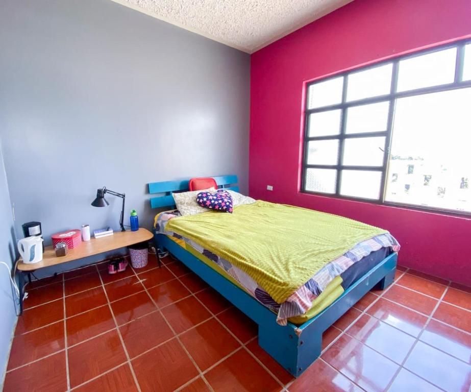 1 dormitorio con cama y pared roja en El Jardín de Banu, en Magdalena Milpas Altas
