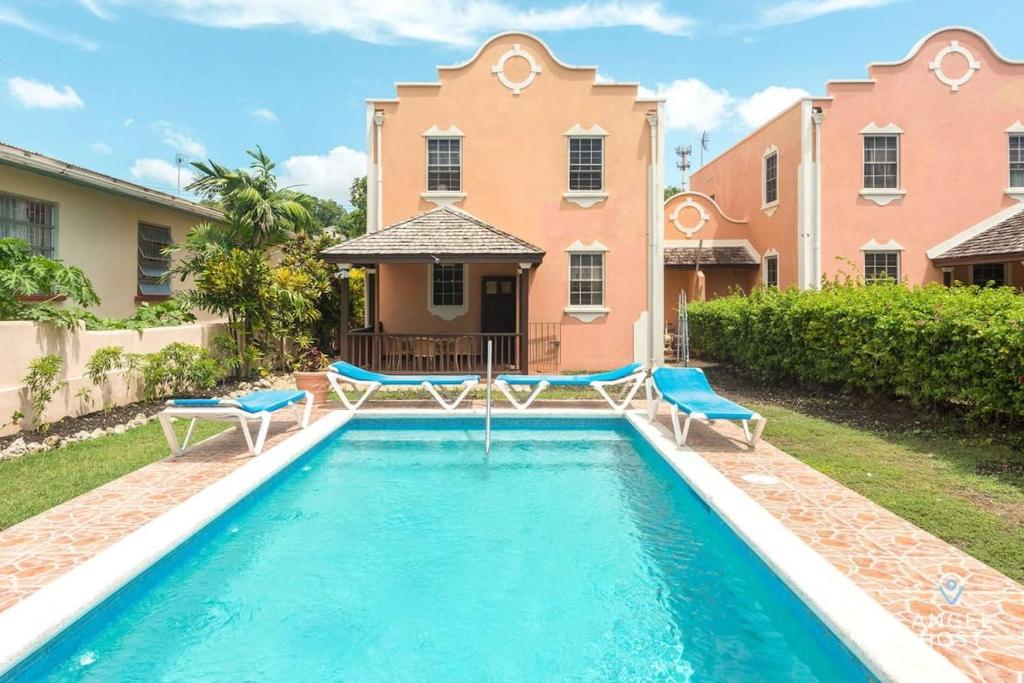 a swimming pool with two chairs and a house at 2-Story Townhome with Private Pool, Ideal for Group! in Christ Church