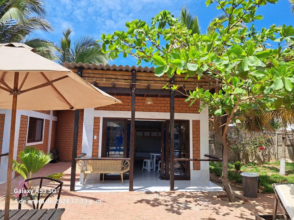 a house with a patio and an umbrella at Punta Pacífico Bungalows Máncora in Máncora