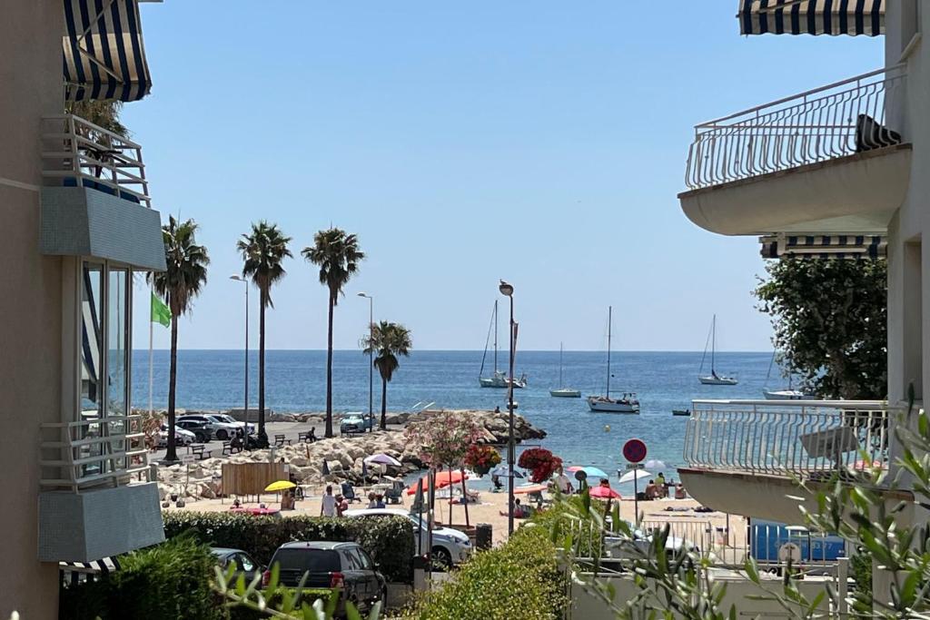 een uitzicht op een strand met palmbomen en boten bij House Facing the sea - Golfe Juan - 4 people in Vallauris