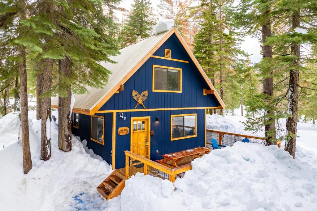 eine blaue Hütte im Wald im Schnee in der Unterkunft Indigo Owl by AvantStay Cabin w Hot Tub Firepit Minutes to Lake Slopes in Homewood