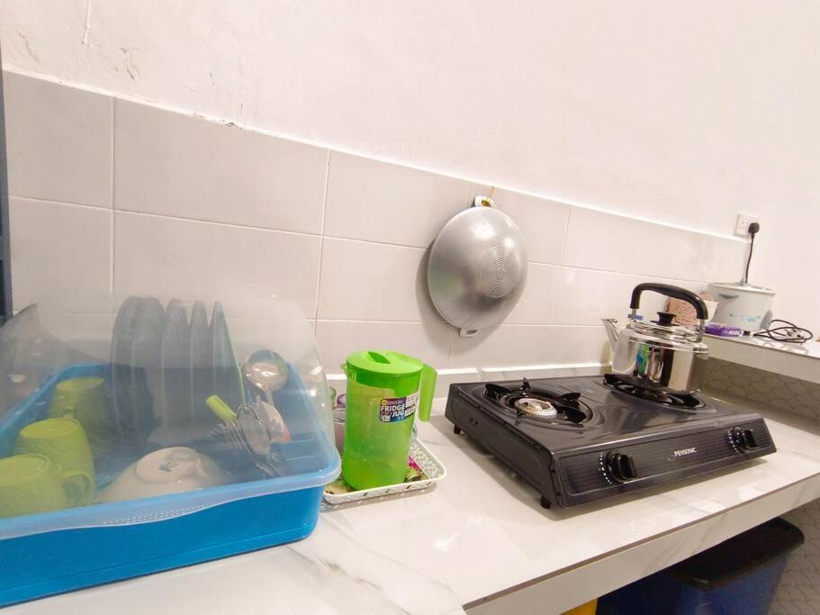a kitchen counter with a plastic container on a stove at Homestay UMAR Sungai Soi in Kuantan