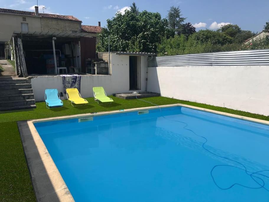 una piscina con 2 sillas y una casa en Maison de campagne 1850 Piscine privée en Aigre