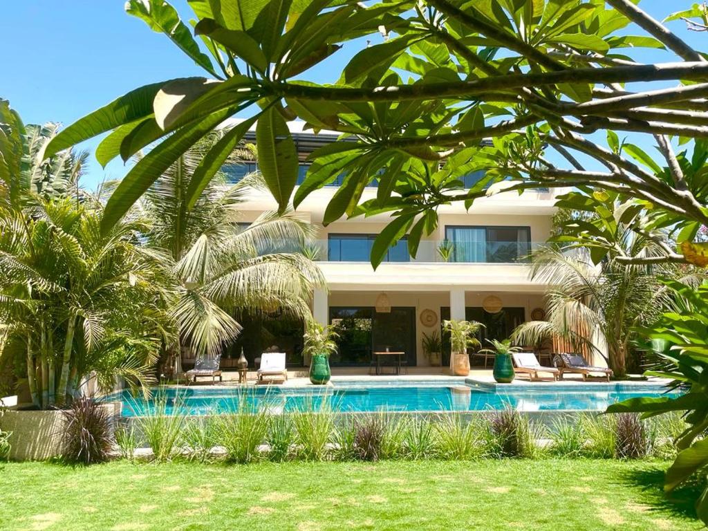 a villa with a swimming pool and palm trees at Villa YEMAYA - Villa d'hôtes in Ngaparou