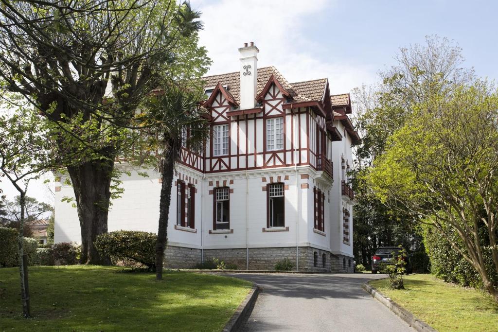 une maison blanche avec un toit en gambrel dans l'établissement Appartement Magnolia 4 étoiles avec parking - Welkeys, à Biarritz