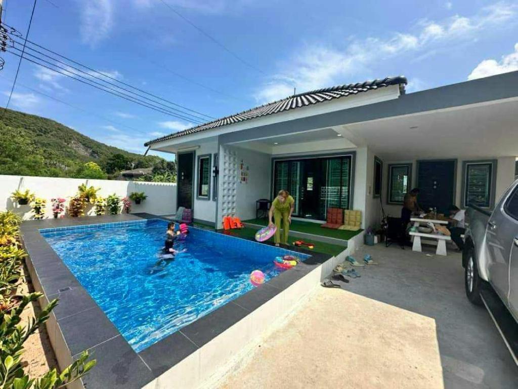 a family playing in a swimming pool in a house at Tai Chon Pool Villa ใต้ชล พูลวิลล่า in Ban Khlot