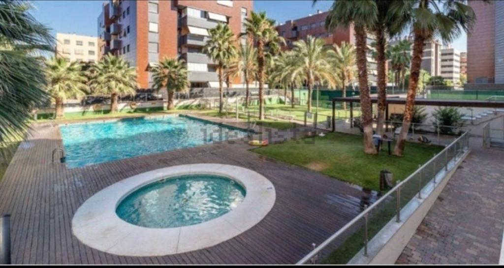 a swimming pool with palm trees and a building at Parque lagos granada in Granada