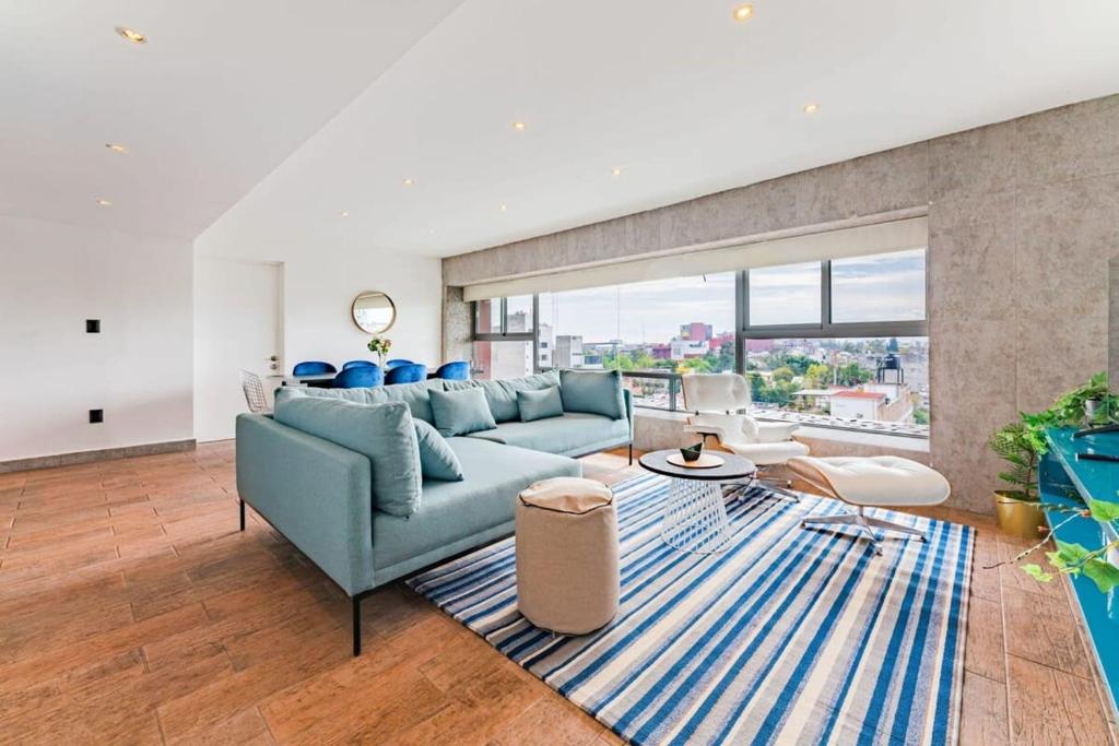 a living room with a blue couch and a large window at Family friendly Roma Condo 247 Security Parking in Mexico City