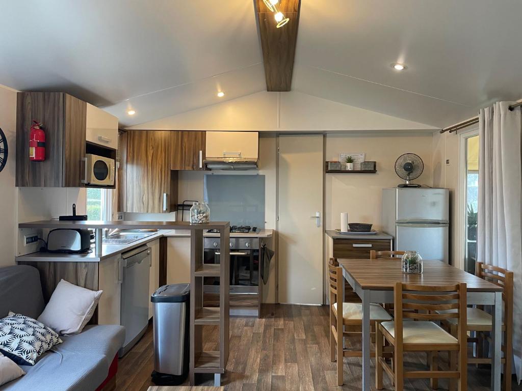 - une cuisine et une salle à manger avec une table et un canapé dans l'établissement Mobile home Cc995 near swimming pool - Les Charmettes, aux Mathes