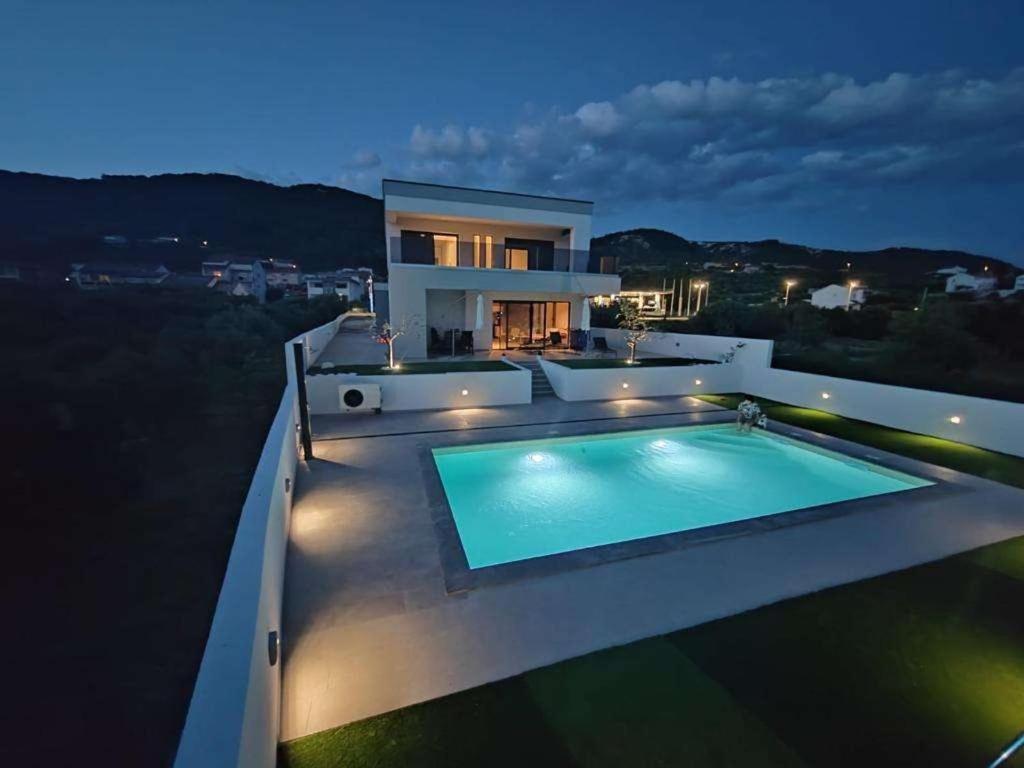 a villa with a swimming pool at night at Holiday house with a swimming pool Banjol, Rab - 22703 in Rab
