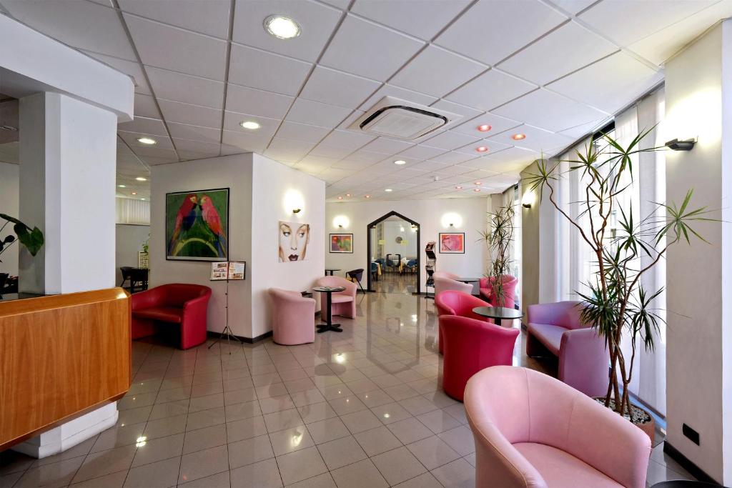 une salle d'attente avec des chaises et des tables roses dans un bâtiment dans l'établissement Tuscia Hotel, à Viterbe
