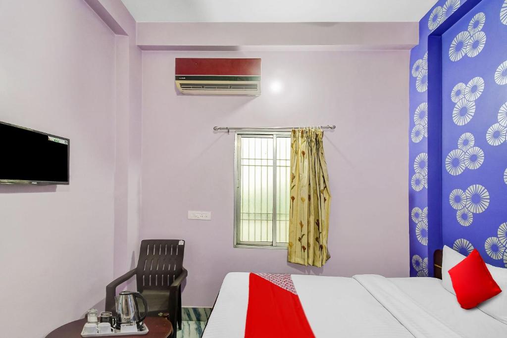 a bedroom with a bed and a chair and a window at Flagship Heritage Inn in Cuttack