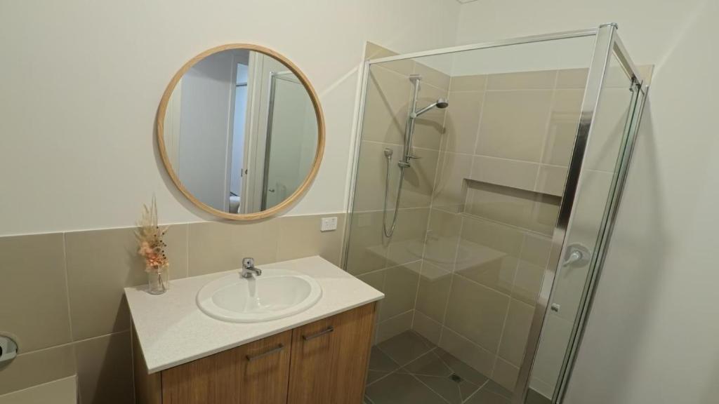 a bathroom with a sink and a shower with a mirror at Brand New House in Lakes Entrance in Lakes Entrance