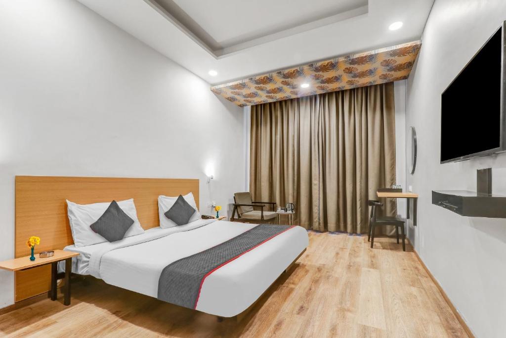 a hotel room with a bed and a flat screen tv at Collection O Hotel Landmark in Lucknow