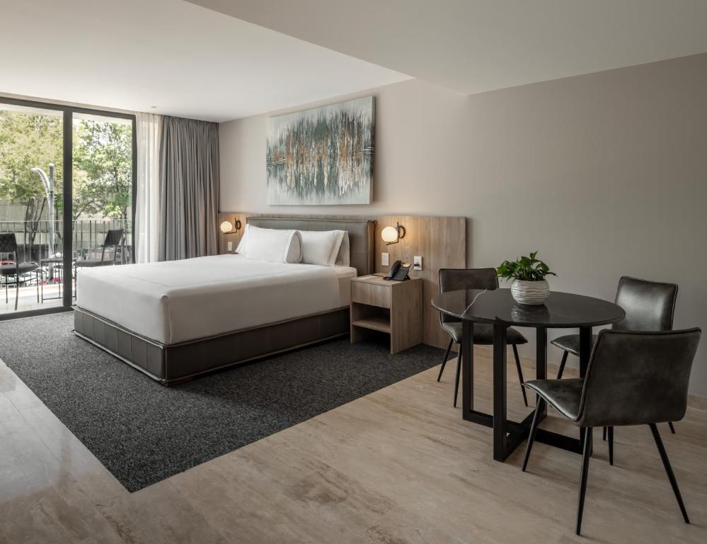 メキシコシティにあるHotel Elements by Marquisのベッドとテーブルが備わるホテルルームです。