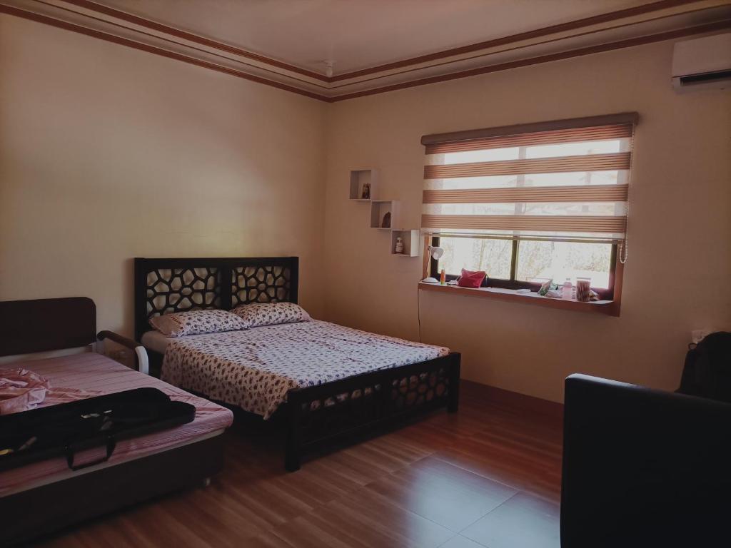 a bedroom with two beds and a window at Bon Joy Bed & Breakfast in Mabini