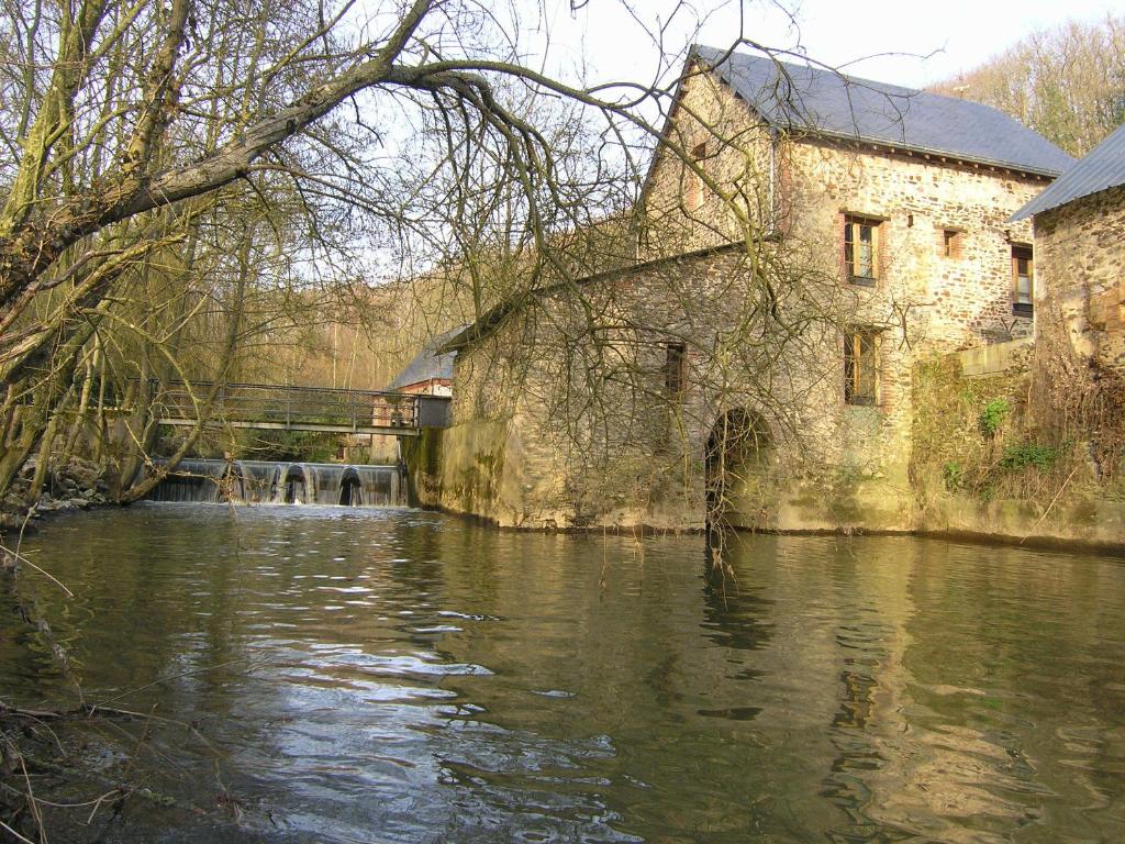un edificio antiguo junto a un río al lado de un edificio en Moulin Du David, en Craon