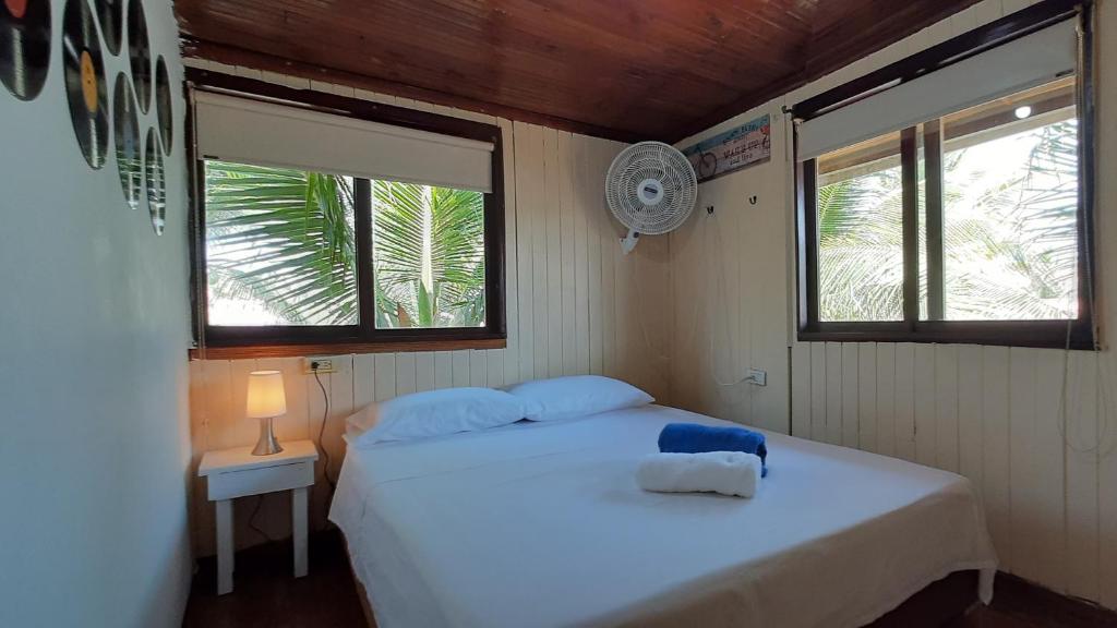 a bedroom with a white bed and two windows at KAZA Balcones in Santa Veronica