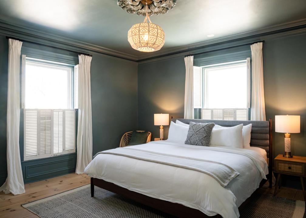 a bedroom with a large bed and two windows at The August House in Windsor