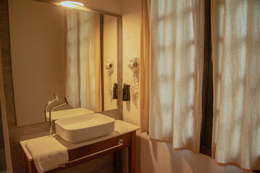 a bathroom with a sink and a mirror at alua pousada ventos de camburi in Camburi