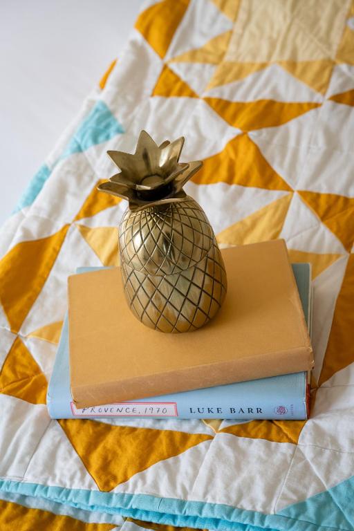 a pineapple on top of two books on a bed at The August House in Windsor