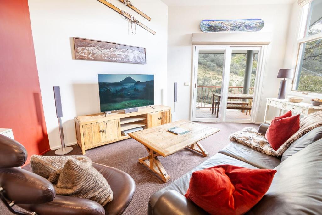 a living room with a couch and a tv at Lhotsky Apartments in Thredbo