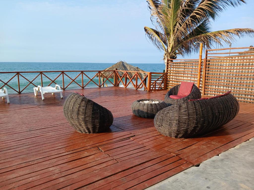 una terraza de madera con sillas y vistas al océano en Casa de Playa Akas, en Canoas de Punta Sal