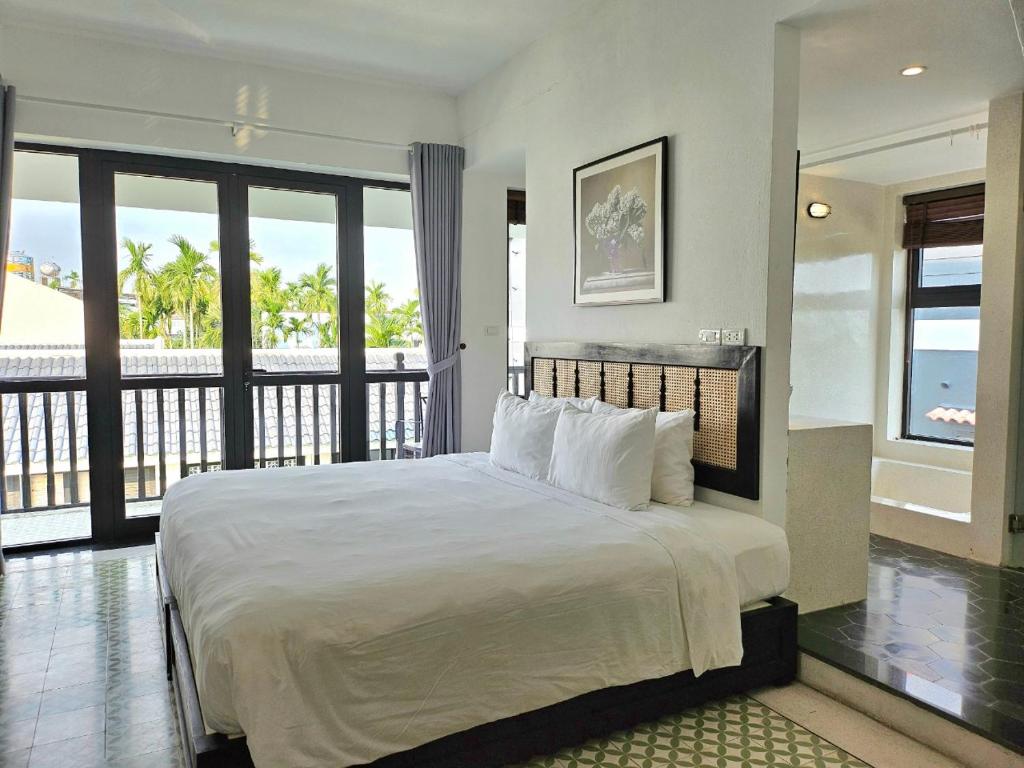 um quarto com uma cama grande e uma varanda em Én Garden Resort Hoian em Hiếu Nhơn