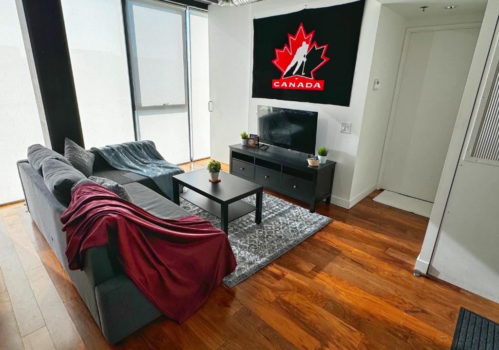 Cozy 1BR Apt - Downtown Winnipeg في وينيبيغ: غرفة معيشة بها أريكة وتلفزيون