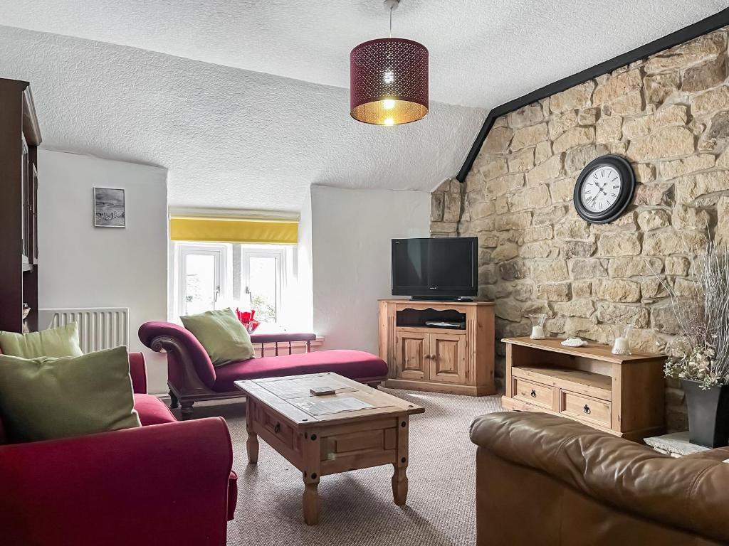 a living room with couches and a stone wall at Smithy Apartment in Matlock