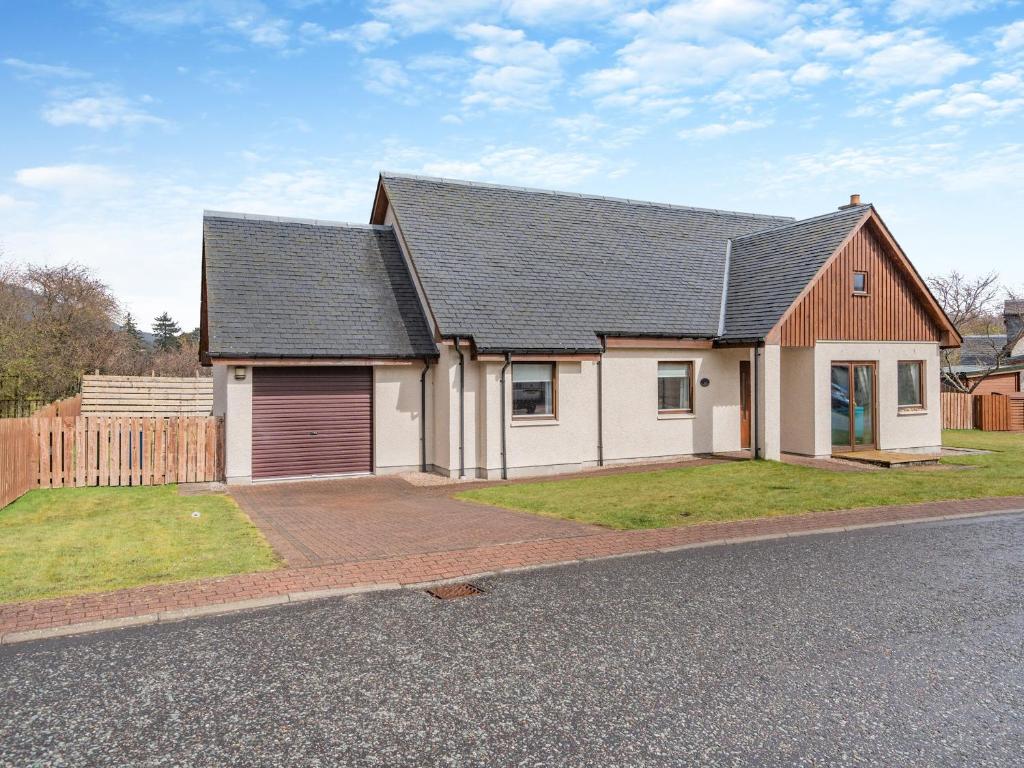 a white house with a black roof on a street at Cairn View - S4402 in Aviemore