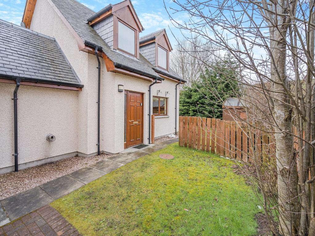 una casa blanca con una puerta marrón y una valla en Coire Cas - S4538, en Aviemore