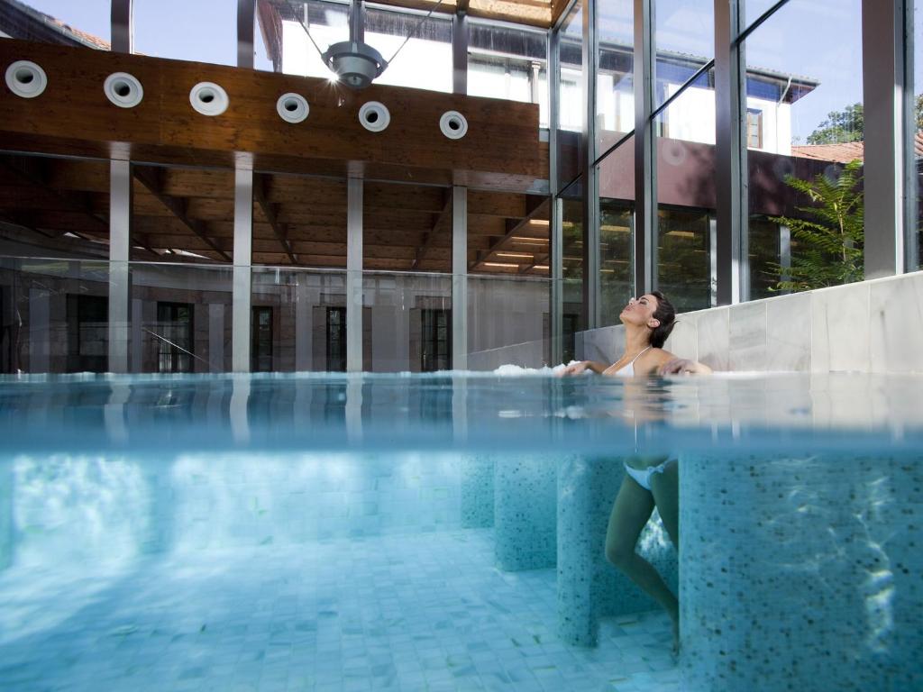 une femme assise dans une baignoire dans une piscine dans l'établissement Gran Hotel Las Caldas by blau hotels, à Las Caldas