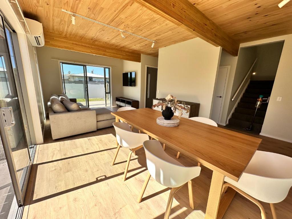 ein Esszimmer mit einem Holztisch und weißen Stühlen in der Unterkunft Stylish 3-bed Taradale Townhouse in Napier
